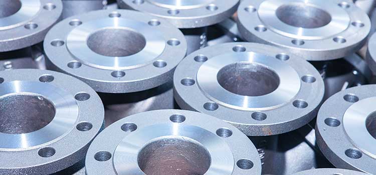 Close-up view of multiple machined metal flanges with precision-drilled holes, arranged in an industrial setting.
